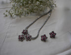 Jewelry set with floral earrings and necklace on a light fabric background