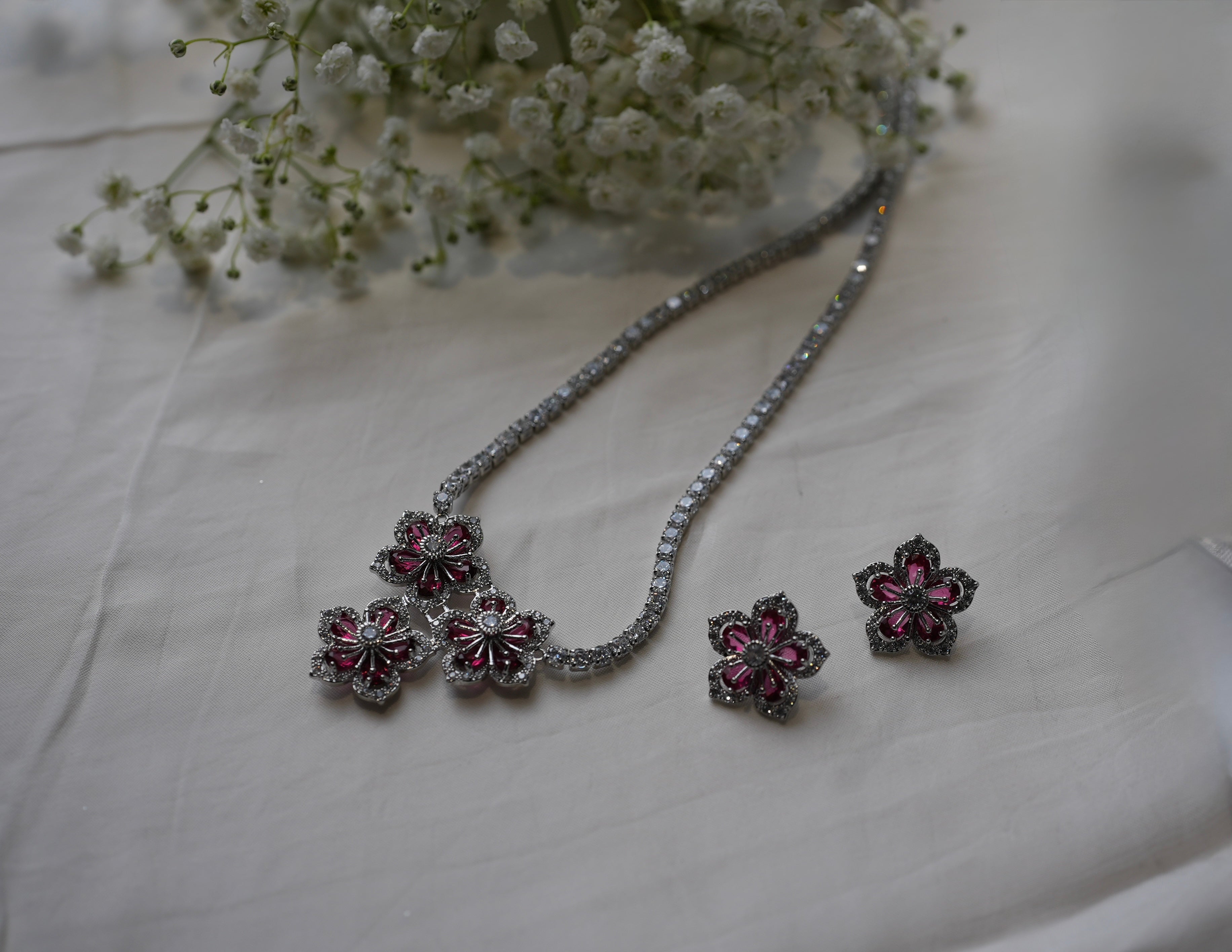 Jewelry set with floral earrings and necklace on a light fabric background