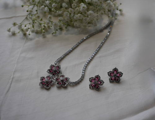 Jewelry set with floral earrings and necklace on a light fabric background