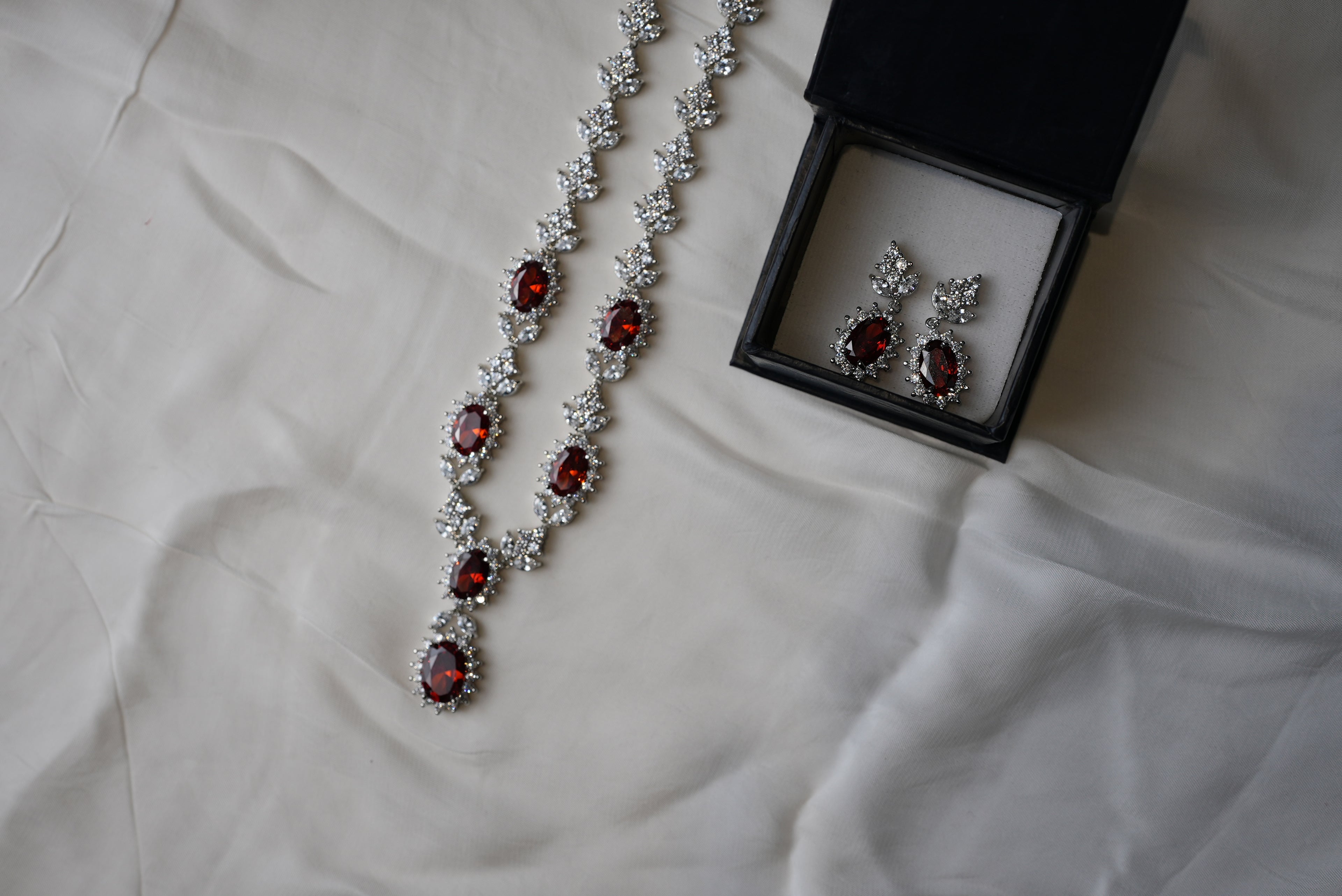 Jewelry set with necklace and earrings on a white fabric background