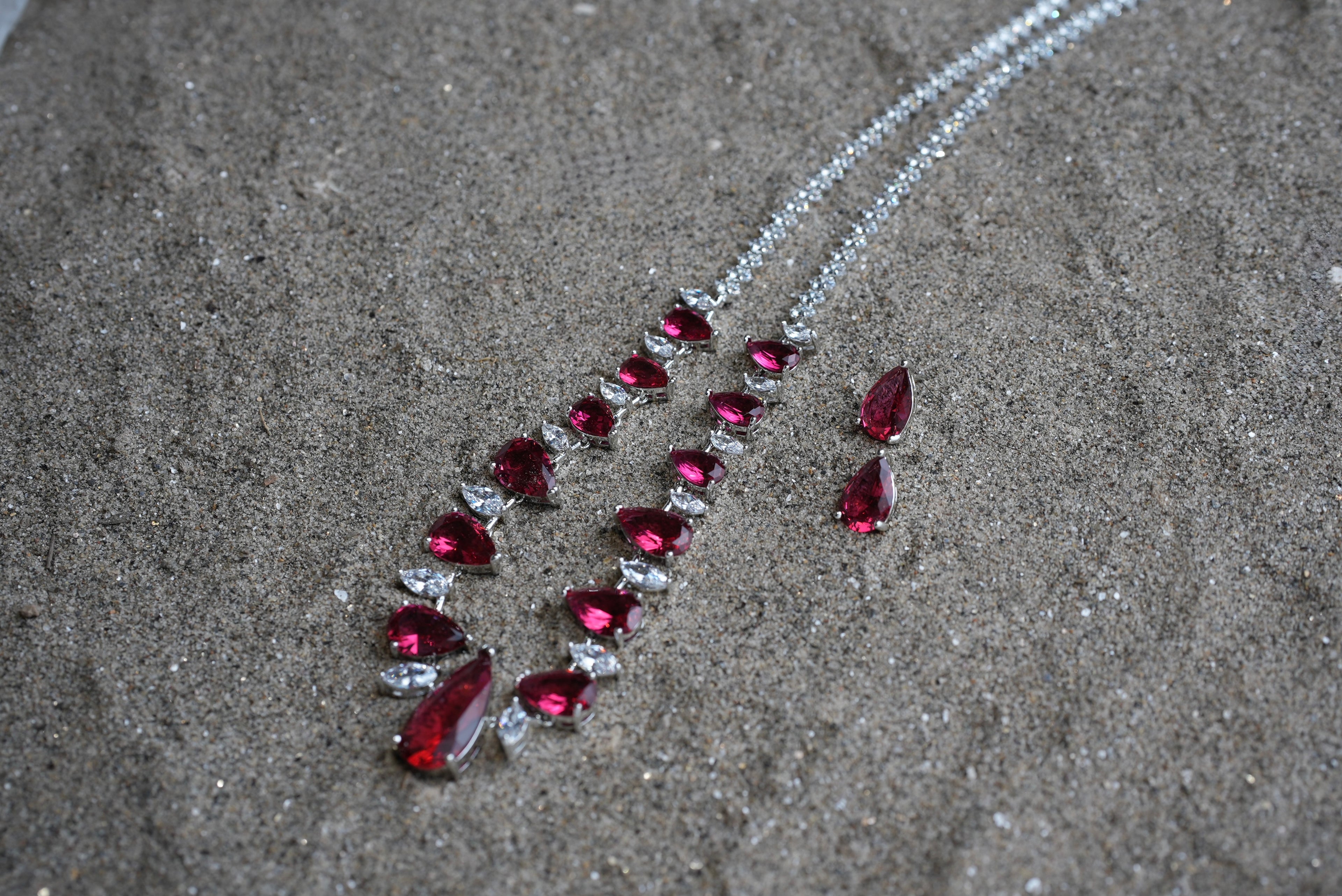 Necklace with red gemstones on a sandy surface