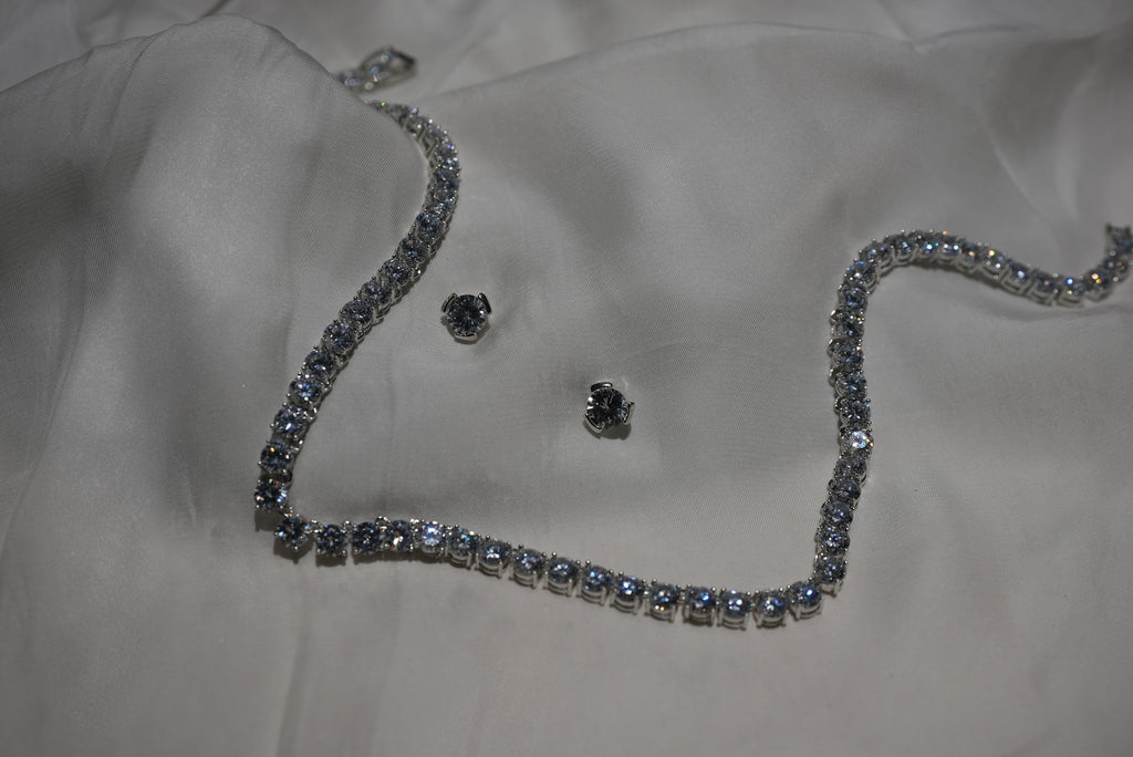 Silver necklace and earrings on a white fabric background