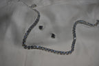Silver necklace and earrings on a white fabric background